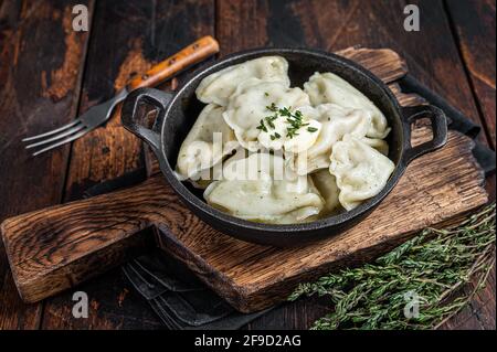 Boulettes maison, varéniki, pierogi farcies de pommes de terre dans une casserole. Arrière-plan en bois sombre. Vue de dessus Banque D'Images