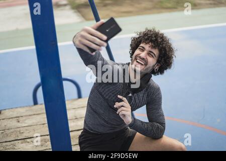 Peu profonde concentration d'un homme caucasien à poil dur dans la prise de vêtements de sport un selfie dans un parc Banque D'Images