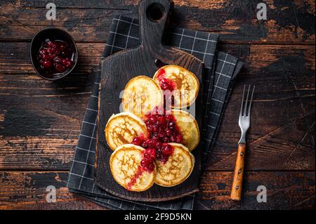 Pile de crêpes au sirop de canneberge sur une planche de bois. Arrière-plan en bois sombre. Vue de dessus Banque D'Images