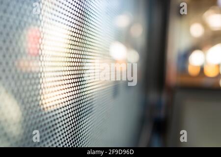 Gros plan sur un film autocollant One Way Vision avec motif à points sur le verre de la fenêtre du train et arrière-plan flou du train de voyageurs et du bokeh. Banque D'Images