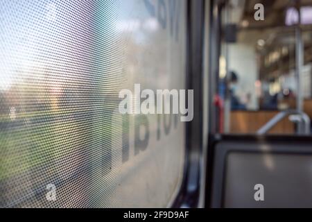 Gros plan sur un film autocollant One Way Vision avec motif à points sur le verre de la fenêtre du train et arrière-plan flou du train de voyageurs et du bokeh. Banque D'Images