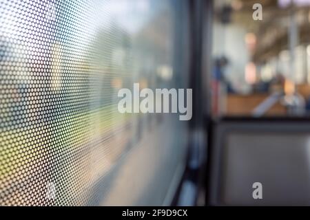 Gros plan sur un film autocollant One Way Vision avec motif à points sur le verre de la fenêtre du train et arrière-plan flou du train de voyageurs et du bokeh. Banque D'Images