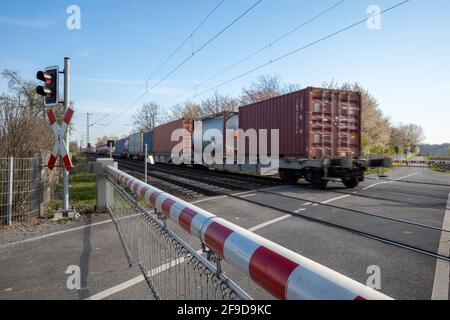 Barrière de chemin de fer à franchissement de niveau rouge et blanc qui bloque la route et la locomotive du train de marchandises se déplacent sur le rail à la campagne en Allemagne. Banque D'Images