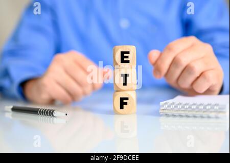 Cubes en bois avec les lettres faisant le mot ETF avec un homme en arrière-plan Banque D'Images