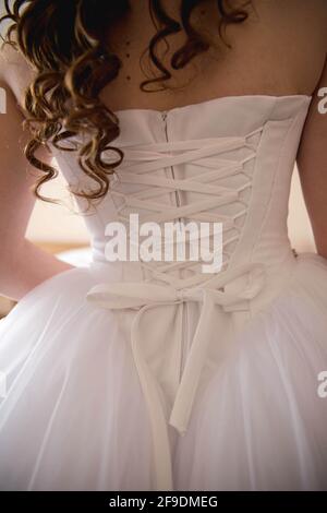 Vue verticale arrière d'une mariée dans une robe avec un corset arrière Banque D'Images