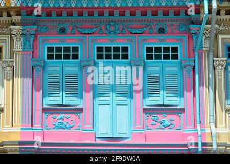 Extérieur de la maison d'achats Peranakan colorée à la façade rose et volets en bois bleu anciens dans la lumière du matin dans la ville historique de Kotong, Singapour Banque D'Images