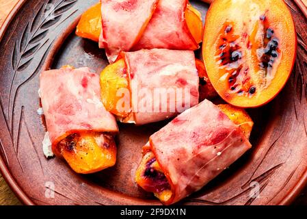 Morceaux de Tamarillo emballés et cuits avec du jambon et du bacon Banque D'Images