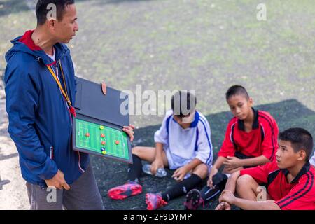 Football entraînement de football pour les enfants. Coach expliquant le plan de jeu. Jeunes garçons améliorant les compétences de football de la Thaïlande locale Banque D'Images