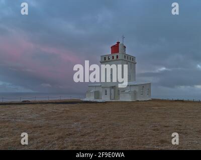 Belle vue sur le phare blanc historique (construit en 1927) sur la péninsule de Dyrhólaey sur la côte sud de l'Islande dans la soirée. Banque D'Images