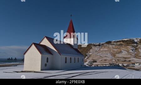 Belle vue sur la petite église située au-dessus du village de Vík í Mýrdal sur la côte sud de l'Islande avec l'océan atlantique et Reynisdrangar formation de roche. Banque D'Images