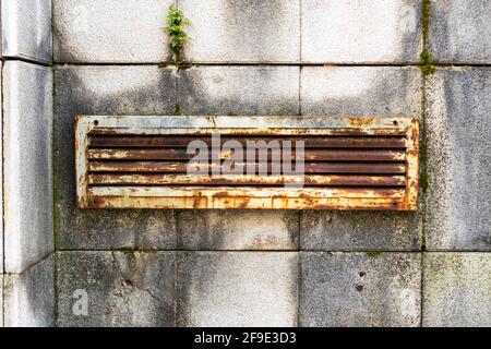 Grille de ventilation en fer rouillé sur un mur délabré avec des carreaux en surcroissance pourris. Gros plan. Grunge concept vintage Banque D'Images