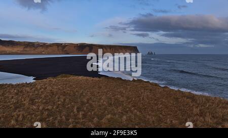 Vue aérienne de la plage volcanique noire de Reynisfjara près du périphérique sur la côte sud de l'Islande avec la célèbre formation rocheuse de Reynisdrangar. Banque D'Images