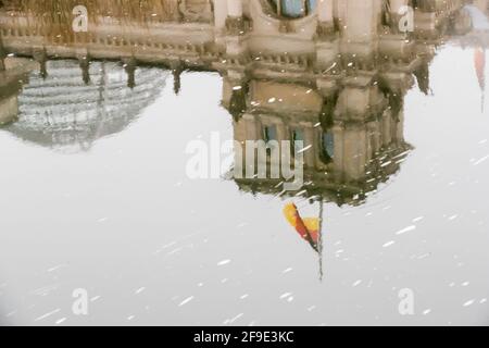 Berlin, Allemagne. 18 avril 2021. Le drapeau allemand sur le bâtiment du Reichstag vole en Berne à l'occasion du mémorial central pour ceux qui sont morts dans la pandémie de Corona en Allemagne et se reflète dans la rivière Spree. Credit: Christoph Soeder/dpa/Alay Live News Banque D'Images