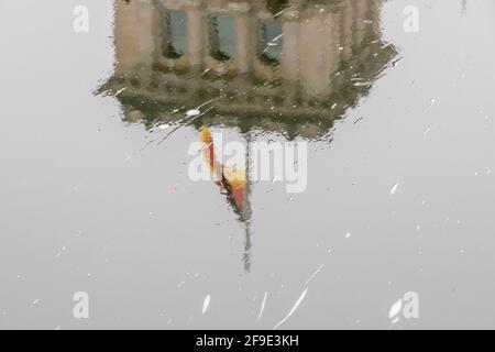 Berlin, Allemagne. 18 avril 2021. Le drapeau allemand sur le bâtiment du Reichstag vole en Berne à l'occasion du mémorial central pour ceux qui sont morts dans la pandémie de Corona en Allemagne et se reflète dans la rivière Spree. Credit: Christoph Soeder/dpa/Alay Live News Banque D'Images