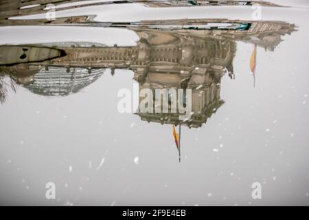 Berlin, Allemagne. 18 avril 2021. Le drapeau allemand sur le bâtiment du Reichstag vole en Berne à l'occasion du mémorial central pour ceux qui sont morts dans la pandémie de Corona en Allemagne et se reflète dans la rivière Spree. Credit: Christoph Soeder/dpa/Alay Live News Banque D'Images