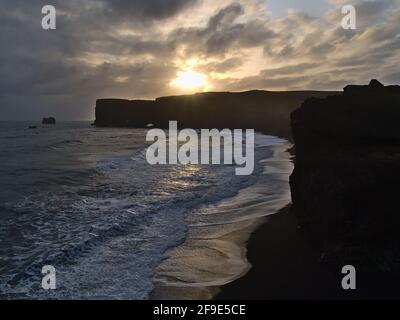Vue imprenable sur les silhouettes des falaises escarpées de la péninsule de Dyrhólaey sur la côte sud de l'Islande près du périphérique avec la plage de Kirkjufjara. Banque D'Images