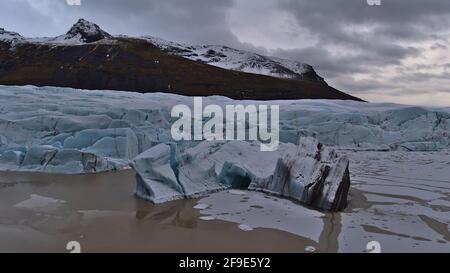 Vue sur le bord de rupture du majestueux Svínafellsjökull, glacier de sortie de la calotte glaciaire de Vatnajökull dans le sud de l'Islande, avec iceberg flottant sur le lac. Banque D'Images