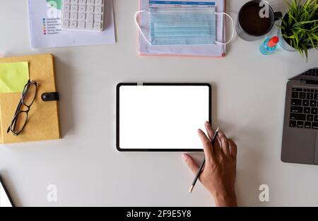 Table de bureau blanche avec masque chirurgical et flacon de désinfectant ou gel d'alcool avec calculatrice isolée sur fond blanc, main de l'homme utilisant Banque D'Images