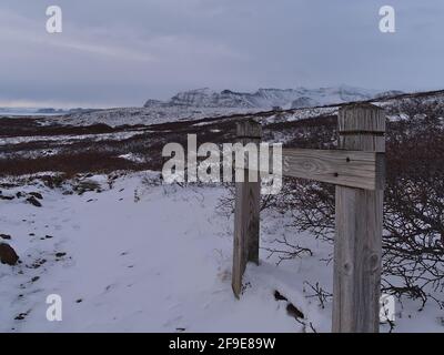 Sentier de randonnée couvert de neige dans le parc national de Skaftafell, dans le sud de l'Islande, avec panneau en bois en forme de flèche indiquant la direction de la cascade Svartifoss. Banque D'Images