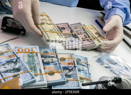 Agent de police spécialisé comptant les billets en dollars dans le laboratoire de la criminalité, image conceptuelle Banque D'Images