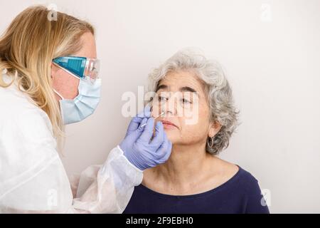 Femme effectuant un test de PCR nasal sur un patient Banque D'Images