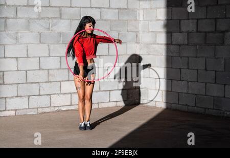 Jeune femme tatouée dans le hila hilule torrenling actif tout en dansant contre les murs de brique avec des ombres Banque D'Images