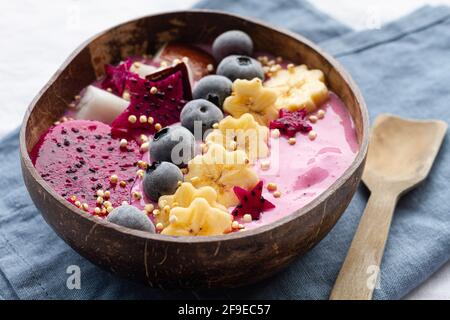 Du dessus du bol de puissance plein de délicieux smoothie près tranches mûres de fruits de banane et de dragon avec bleuets pour le petit déjeuner Banque D'Images