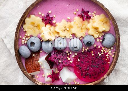 Du dessus du bol de puissance plein de délicieux smoothie près tranches mûres de fruits de banane et de dragon avec bleuets pour le petit déjeuner Banque D'Images