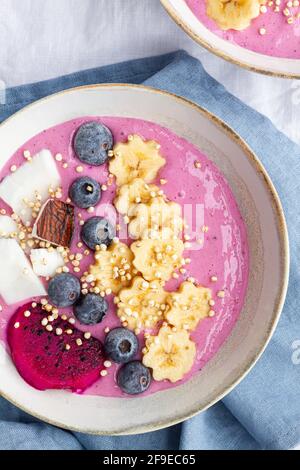 Du dessus du bol de puissance plein de délicieux smoothie près tranches mûres de fruits de banane et de dragon avec bleuets pour le petit déjeuner Banque D'Images