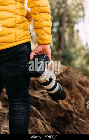 Vue arrière d'un photographe anonyme tenant son appareil photo la montagne avec un arrière-plan flou Banque D'Images