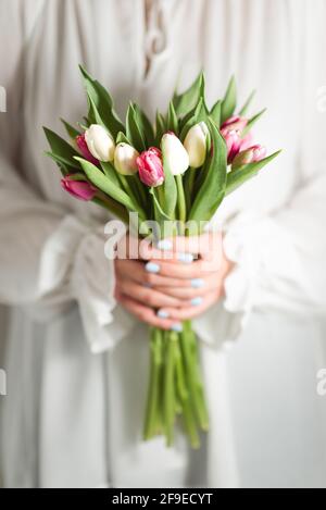 Croiser une femme méconnaissable dans une robe romantique debout avec un bouquet de fleurs tendres et colorées Banque D'Images