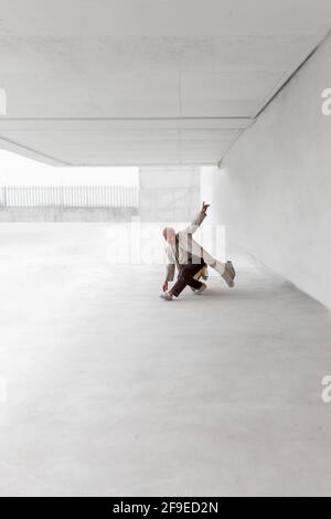 Danseuse masculine montrant le mouvement de breakdance tout en équilibrant sur les bras et Réalisation de sauts manuels sur sol en béton en zone urbaine Banque D'Images