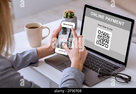 Une femme méconnaissable scanne un code qr par smartphone depuis un ordinateur portable Banque D'Images