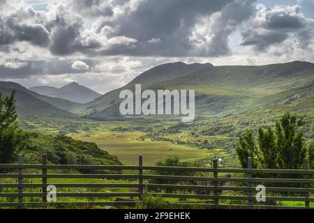 Vue de l'arrière de la clôture en bois sur le magnifique Molls Gap avec la vallée de la rivière Owenreagh et les montagnes MacGillycuddys Reeks, Ring of Kerry, Irlande Banque D'Images