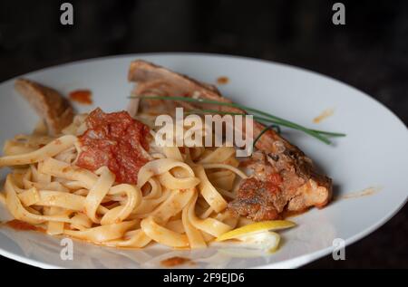 Un déjeuner avec des côtes d'agneau sur des nouilles au ruban et de la tomate sauce devant un fond sombre Banque D'Images