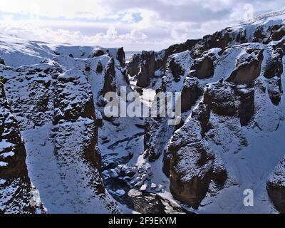 Vue imprenable sur le populaire canyon Fjaðrárgljúfur dans le sud de l'Islande près de la route 1 avec des rochers enneigés, des falaises abruptes et la rivière sinueuse Fjaðrá. Banque D'Images