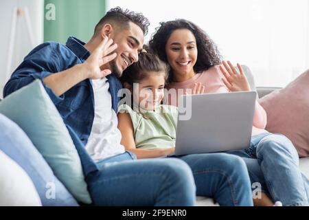 Joyeux parents arabes et fille de passer des appels vidéo avec ordinateur portable À la maison Banque D'Images