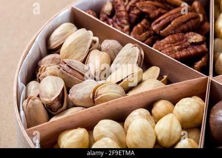 boîte en bois avec des cellules pour différents fruits à coque nourriture pour la nutrition des protéines saines pistache gros plan, personne. Banque D'Images