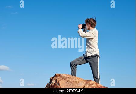 Un jeune homme aventureux espagnol se tenant sur un rocher porter un masque et utiliser des jumelles Banque D'Images