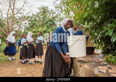 Dodoma, Tanzanie. 08-18-2019. Une belle adolescente noire de Tanzanie sourit à la caméra tout en se lavant les mains après avoir déjeuné au sch Banque D'Images