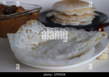 Trémies et crêpes de riz. Deux types de plats de petit-déjeuner de riz rouge avec curry de poulet fait avec du masala maison moulu. Prise de vue sur fond blanc. Banque D'Images