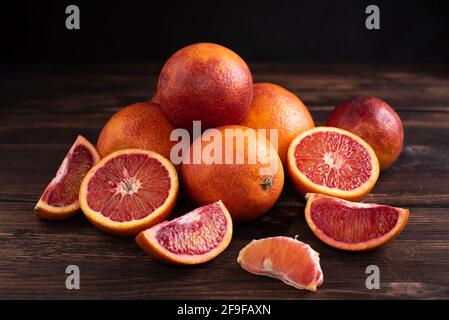 Colline d'orange de sang frais juteux sur fond de bois foncé, nourriture saine, style rustique, gros plan. Banque D'Images