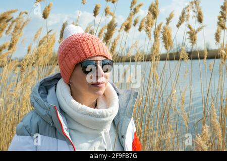 Une femme d'âge moyen marche à l'extérieur au début du printemps sur la rivière. La femme est habillée dans un style sportif. Banque D'Images