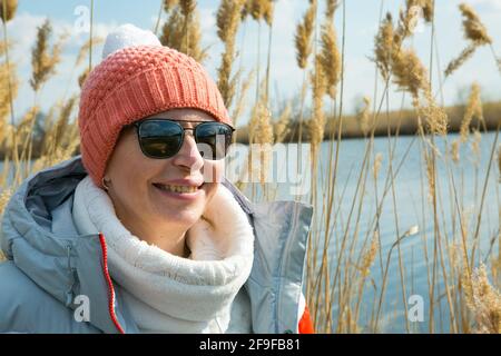 Une femme d'âge moyen marche à l'extérieur au début du printemps sur la rivière. La femme est habillée dans un style sportif. Banque D'Images