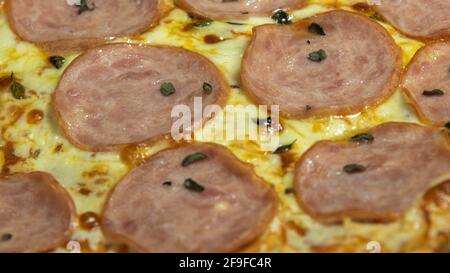 Pizza au filet fumé maison et mozzarella sur fond de nappe à carreaux bleus. Cuisine italienne. Plat à pizza maison. Banque D'Images