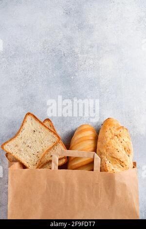 Mélange de pain dans un sac de papier sur une table en pierre en béton gris clair. Vue de dessus avec espace de copie Banque D'Images