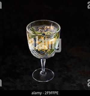 Buvez de l'alcool avec du citron, du romarin et de la glace sur une table noire. Cocktail glacé avec citron et herbes. Espace pour le texte. Photo pour le menu. Banque D'Images