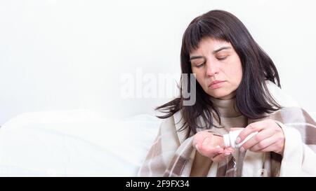 Portrait de la femme malade, couverte de couverture, prenant des pilules pour traiter les maux de tête, copier l'espace. Concept de santé. Maladie saisonnière, allergie, grippe concept Banque D'Images