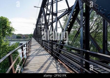 Chemin piétonnier à côté d'un chemin de fer en été sur un pont structuré en métal noir Banque D'Images