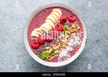 Smoothie à la framboise rose saine avec diverses garnitures supraalimentaires isolées sur fond de béton, vue du dessus Banque D'Images